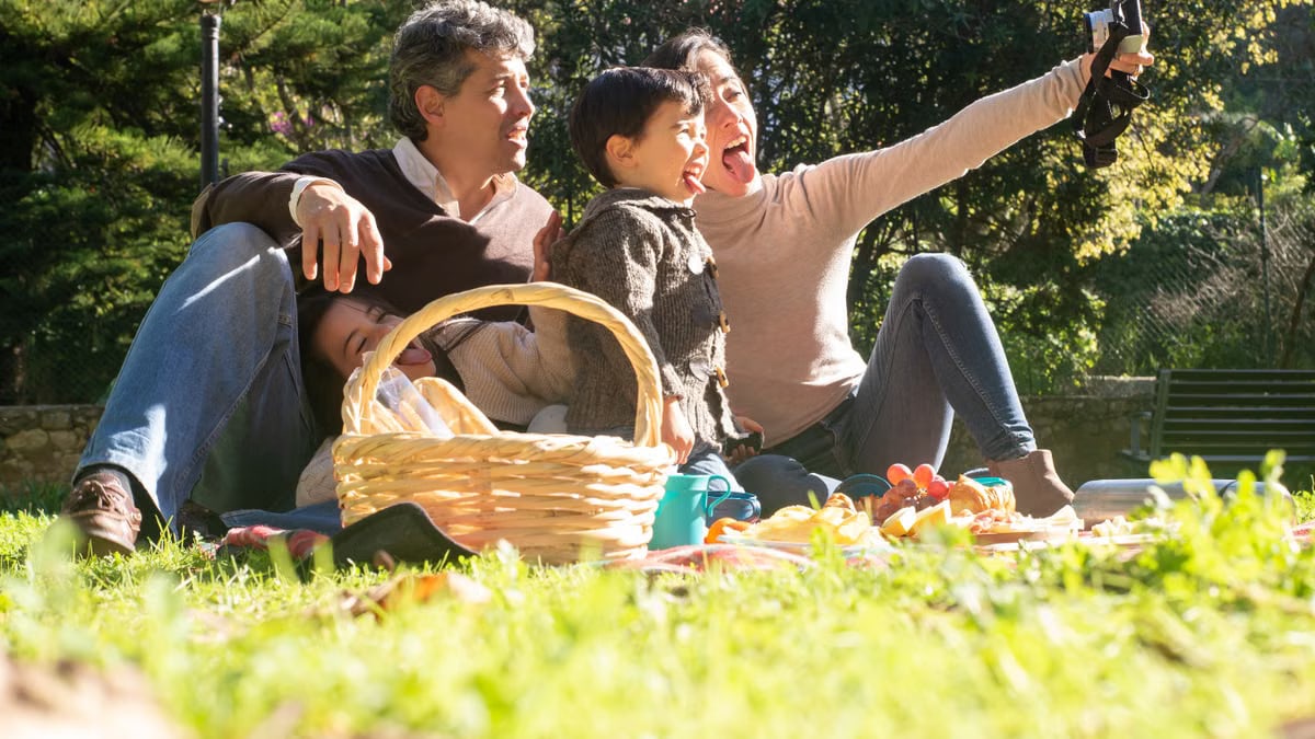 A happy family captures a selfie during a sunny picnic in a Portuguese park.